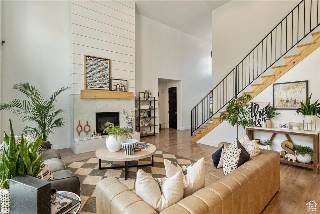 Living area with wood finished floors, a towering ceiling, stairway, a fireplace, and baseboards