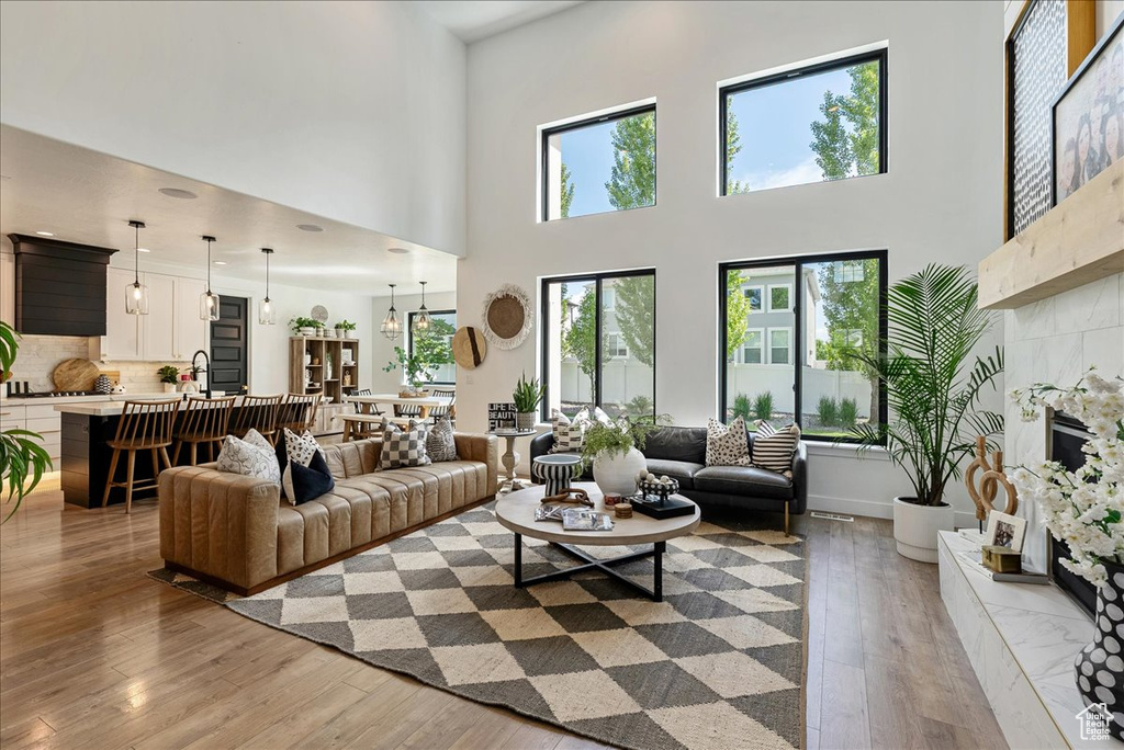Living room featuring a fireplace, light wood-style flooring, and a high ceiling