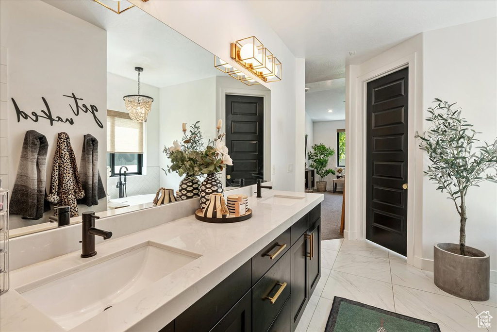 Full bathroom with marble finish floors, double vanity, a chandelier, and baseboards