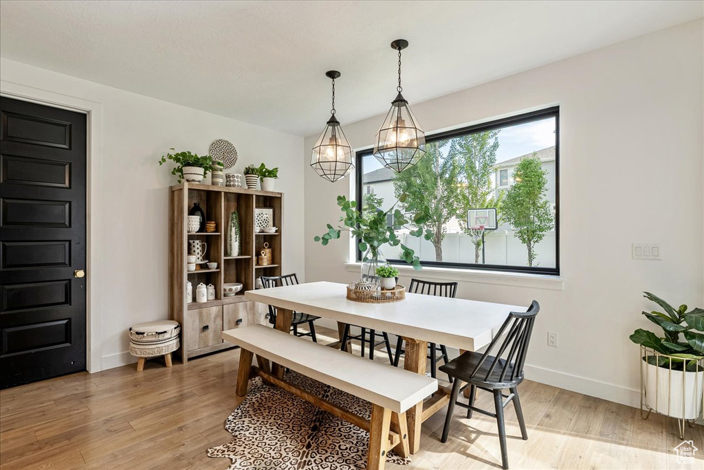 Dining space featuring light wood finished floors, a chandelier, and baseboards