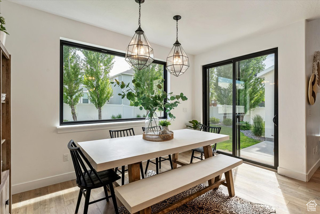 Dining space featuring healthy amount of natural light, light wood-style floors, baseboards, and a chandelier