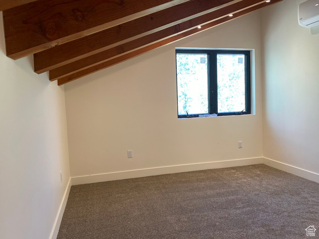 Additional living space with a wall mounted air conditioner, carpet floors, and baseboards