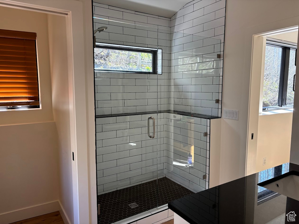 Full bathroom with a stall shower, a baseboard radiator, baseboards, and wood finished floors