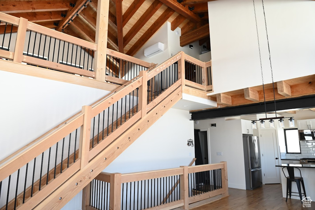 Stairs with high vaulted ceiling, beam ceiling, and wood finished floors