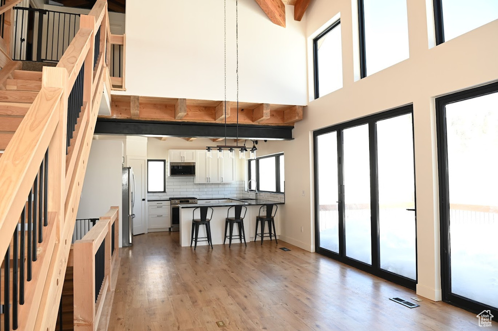 Kitchen with stainless steel appliances, a kitchen breakfast bar, a peninsula, a high ceiling, and backsplash