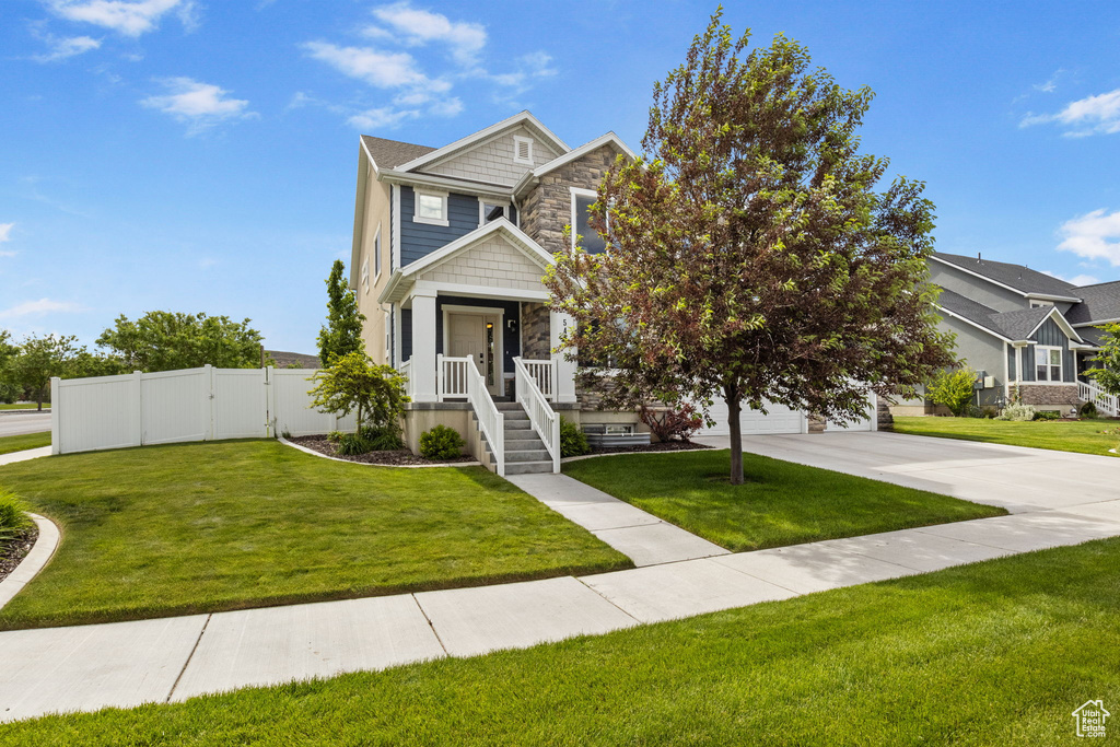 View of front of house featuring stone siding, driveway, a garage, and a gate