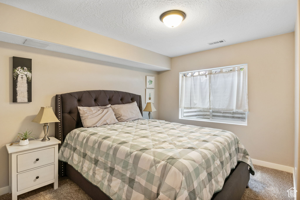 Bedroom with carpet floors, baseboards, and a textured ceiling