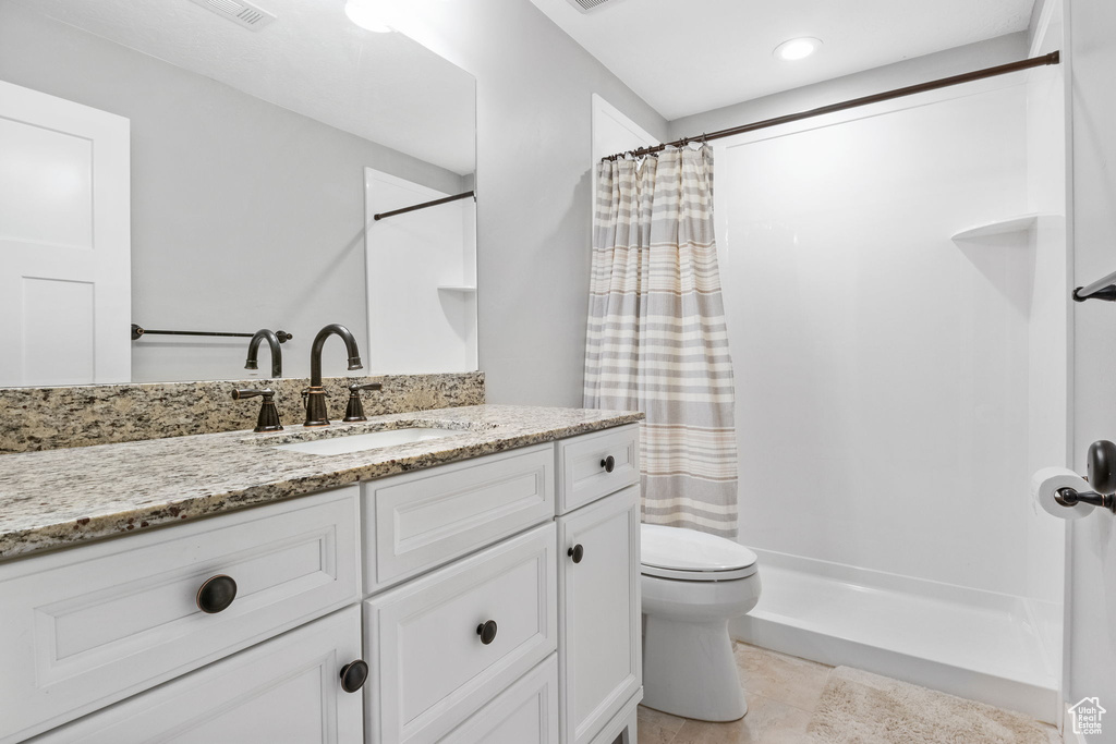 Bathroom with a shower with curtain, vanity, toilet, and tile patterned floors