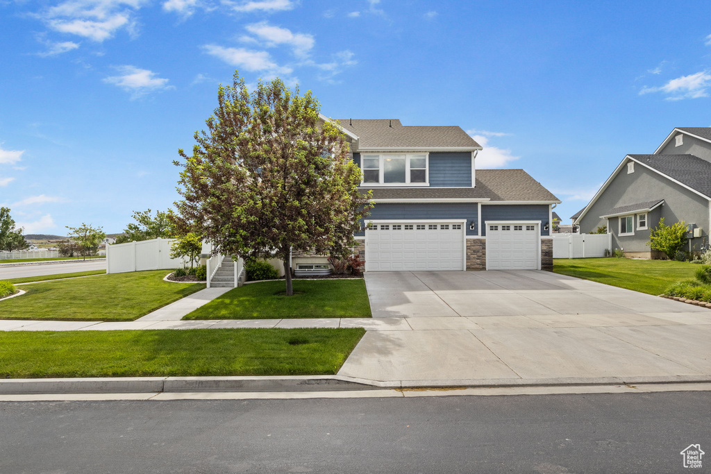 View of front of property with stone siding, driveway, and a garage