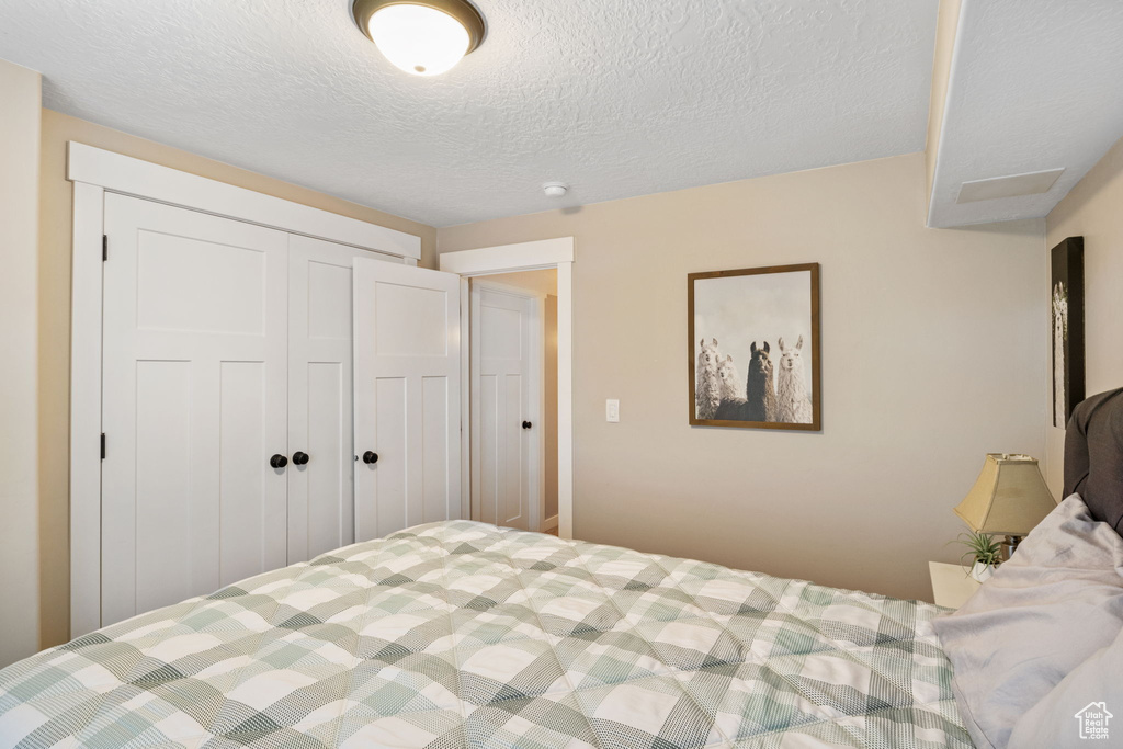 Bedroom with a textured ceiling and a closet