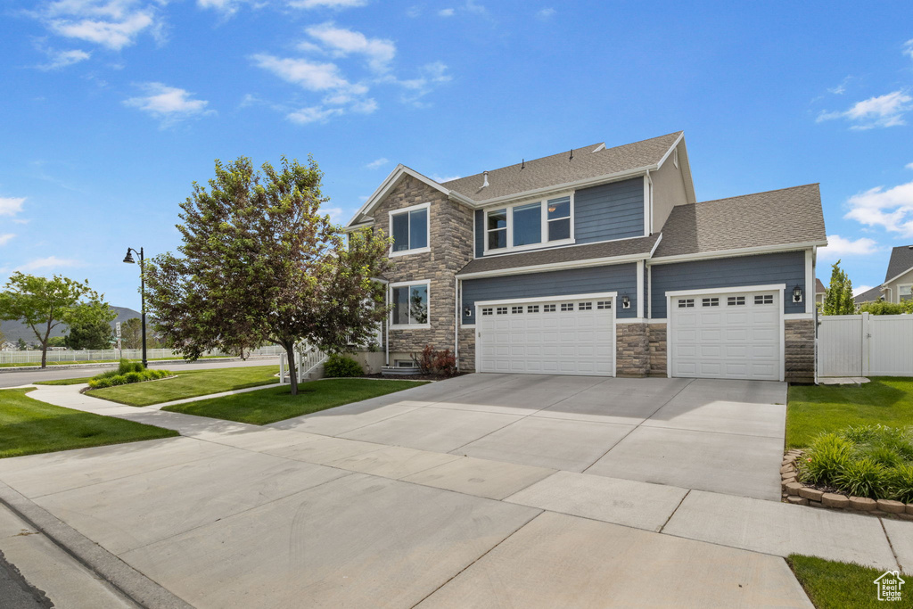 View of front of home featuring stone siding, driveway, a shingled roof, a gate, and an attached garage