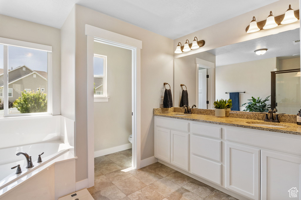 Full bath with double vanity, a garden tub, a shower stall, and toilet