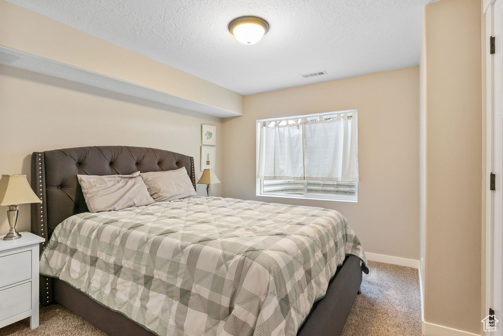 Bedroom with carpet floors, baseboards, and a textured ceiling