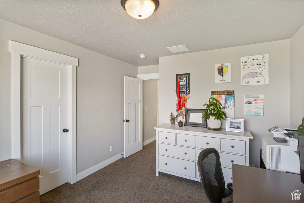 Office space featuring dark carpet, baseboards, and a textured ceiling