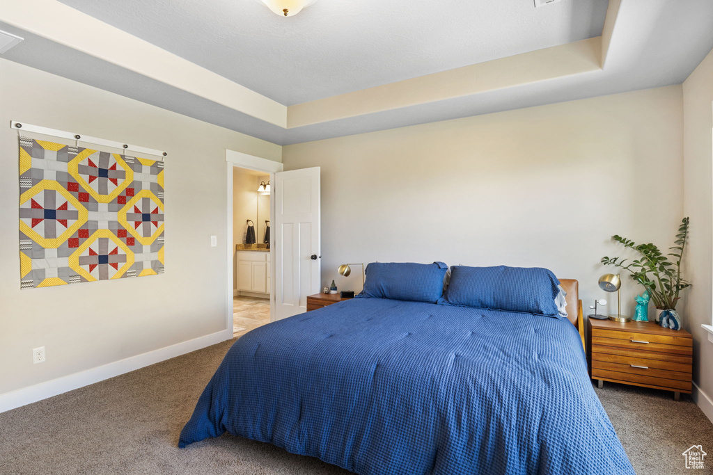 Carpeted bedroom featuring baseboards, connected bathroom, and a tray ceiling
