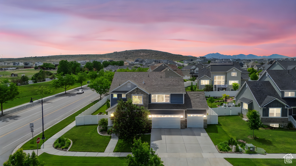 View of front of home with a residential view, driveway, stone siding, a mountain view, and a garage
