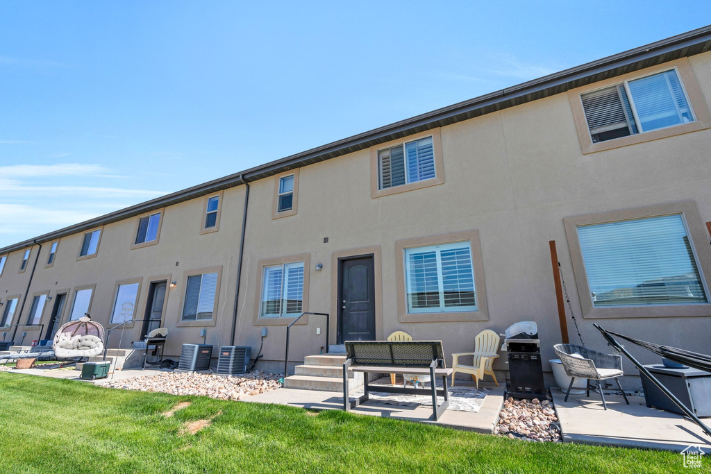 Rear view of property featuring central air condition unit, a patio area, stucco siding, and a yard