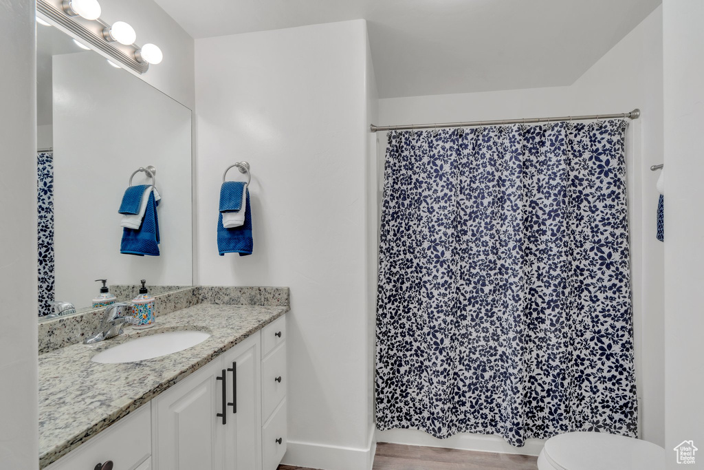 Full bath featuring vanity, toilet, a shower with shower curtain, and baseboards
