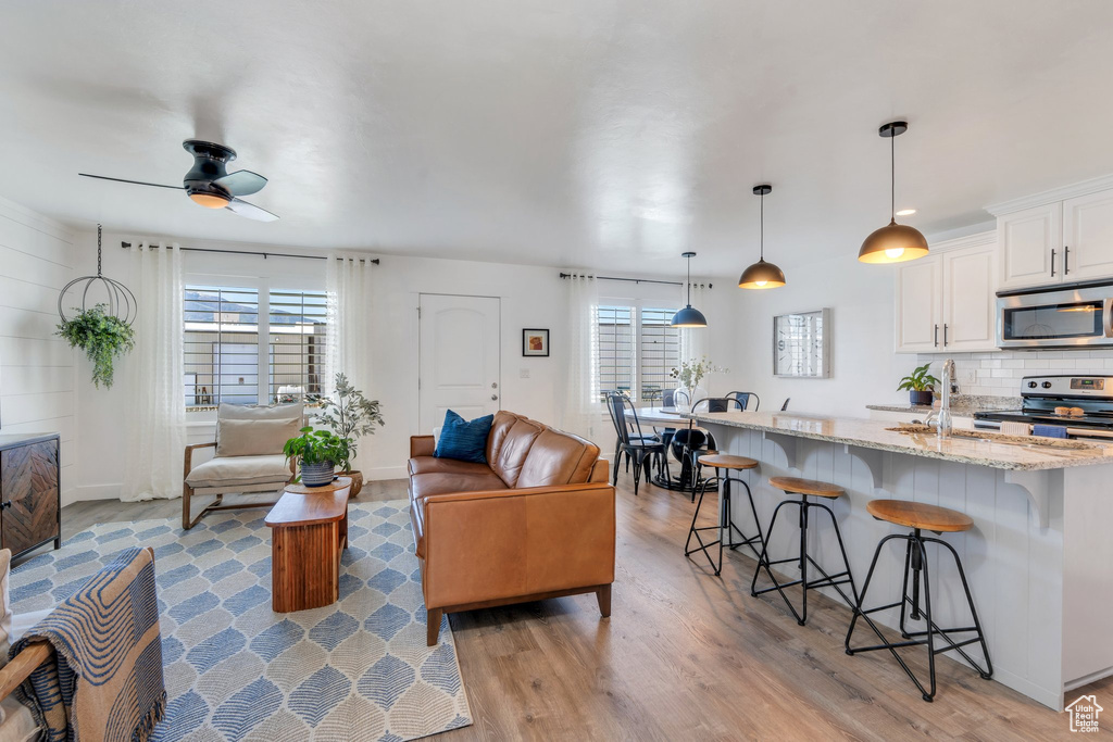 Living area featuring light wood-type flooring, ceiling fan, and baseboards