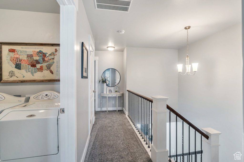 Hall featuring independent washer and dryer, carpet floors, an upstairs landing, a chandelier, and baseboards