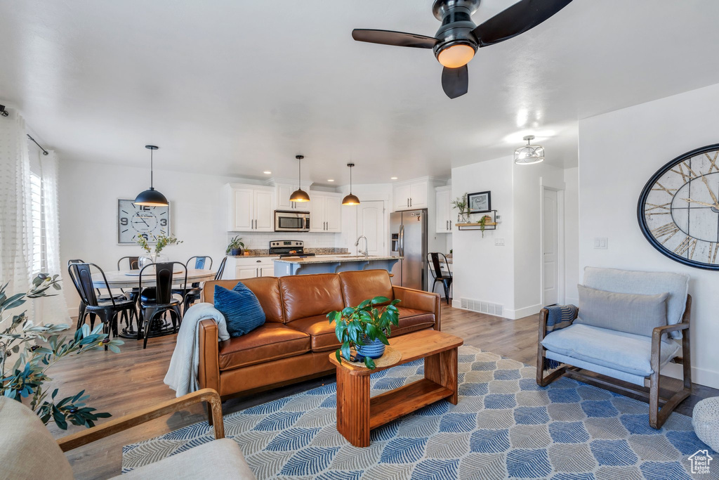 Living area with wood finished floors, a ceiling fan, and baseboards