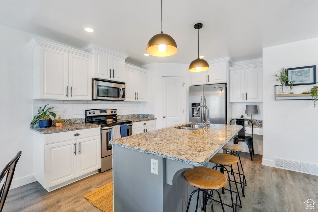 Kitchen featuring appliances with stainless steel finishes, a sink, baseboards, white cabinetry, and recessed lighting