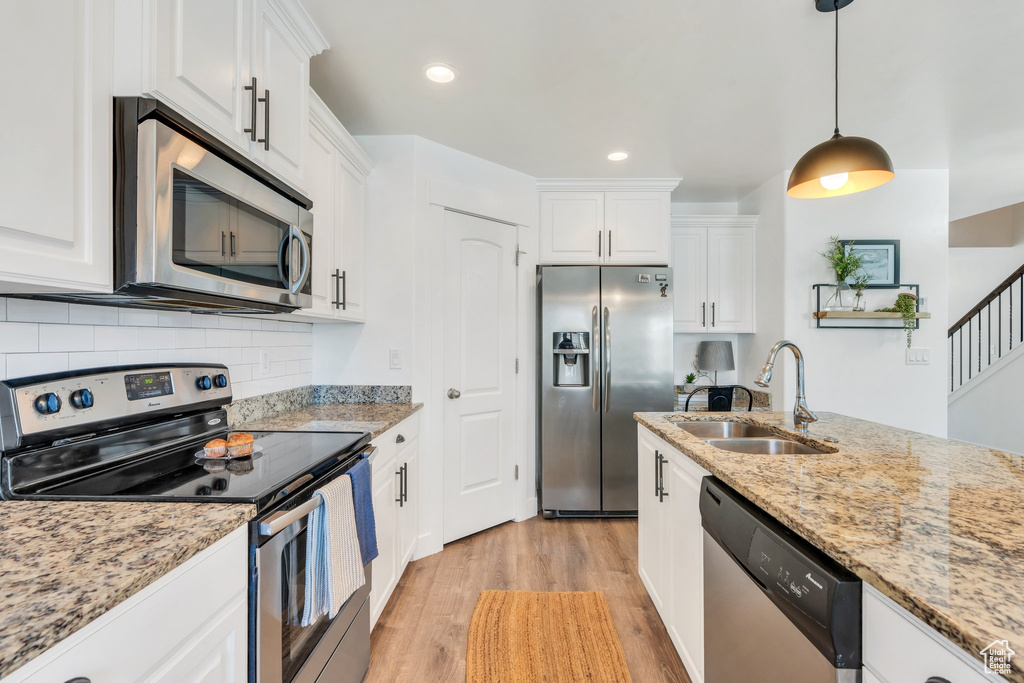 Kitchen featuring appliances with stainless steel finishes, light wood-style floors, a sink, white cabinetry, and recessed lighting