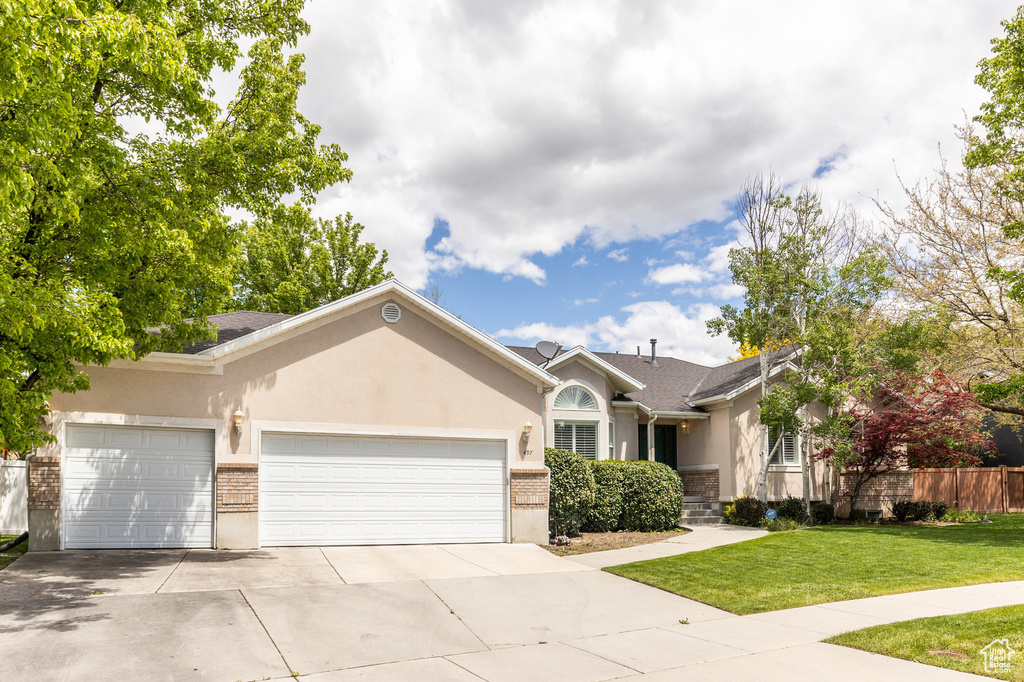 Single story home featuring an attached garage, driveway, stucco siding, and brick siding