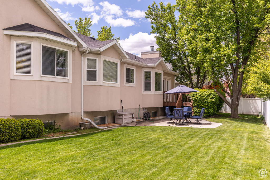 Rear view of property featuring a patio area, a chimney, roof with shingles, and stucco siding
