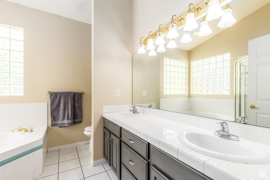 Bathroom with a garden tub, double vanity, toilet, tile patterned flooring, and baseboards