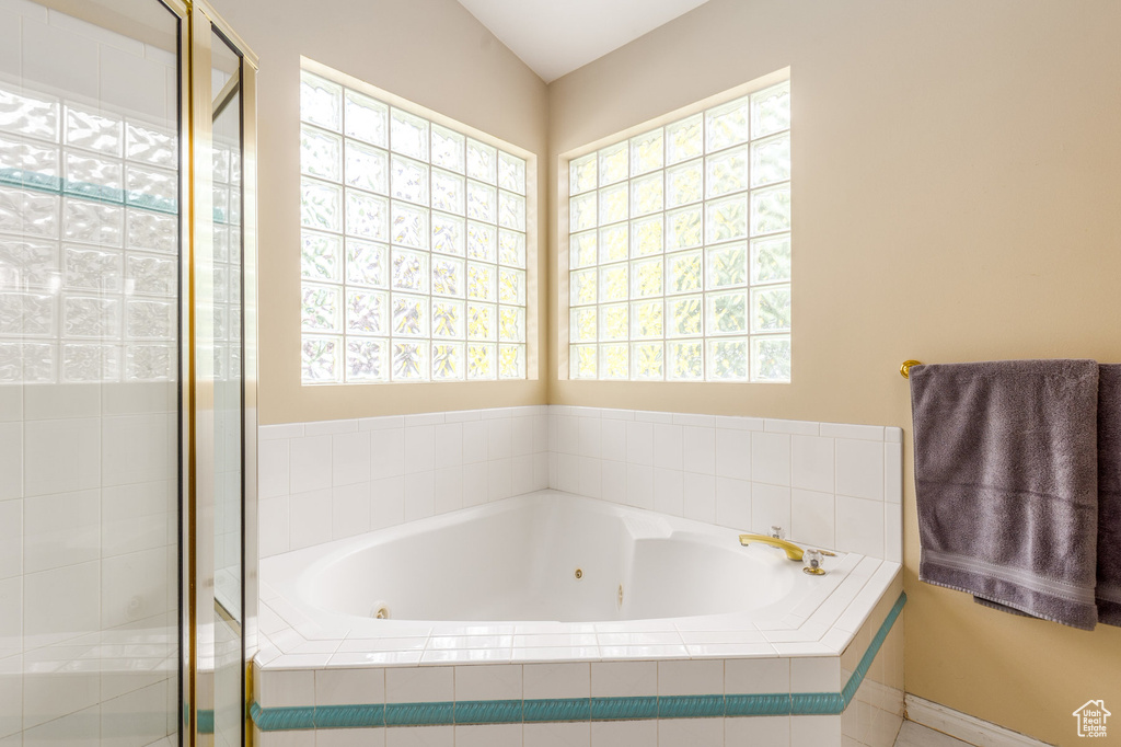 Bathroom featuring a whirlpool tub, plenty of natural light, and a stall shower