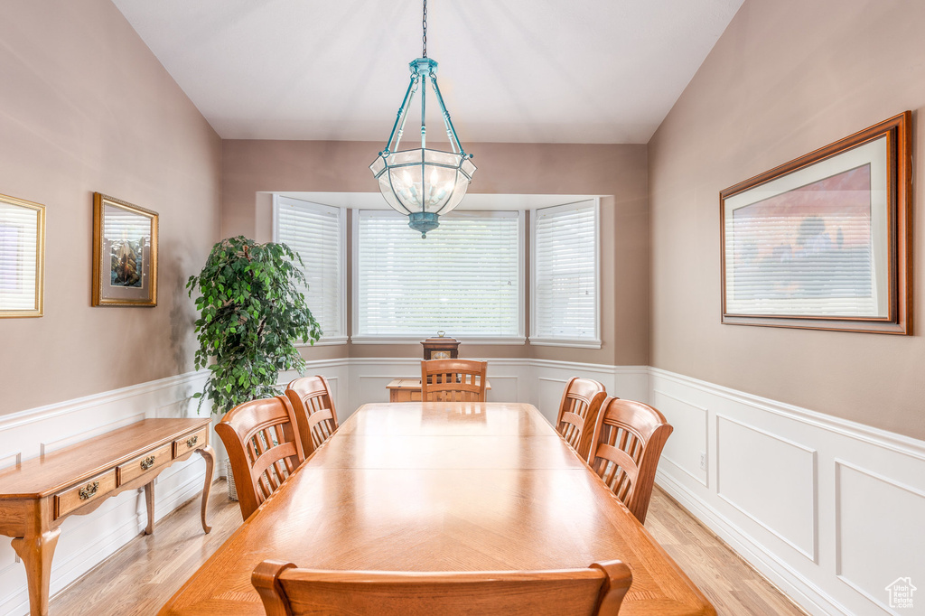 Dining area with light wood-style floors, a wainscoted wall, and a decorative wall