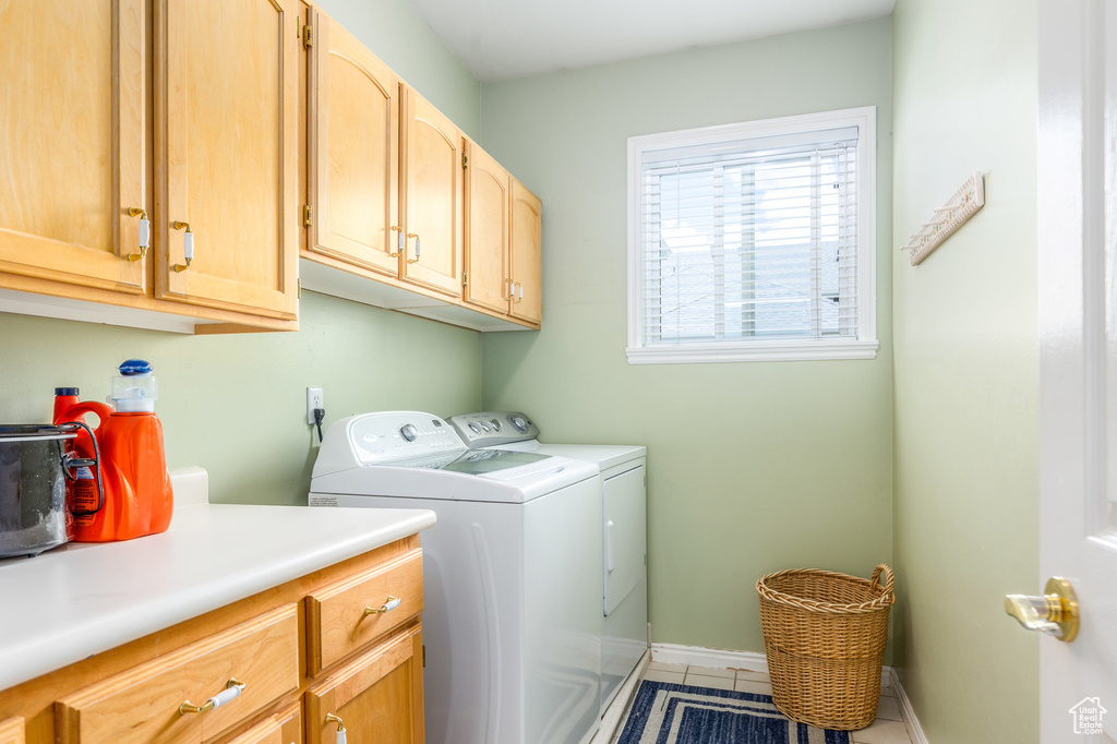 Laundry area with cabinet space, washing machine and clothes dryer, tile patterned floors, and baseboards