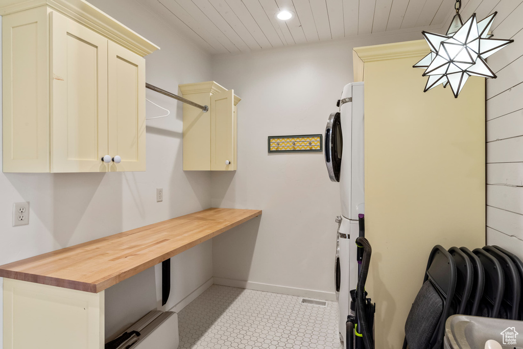 Laundry area with stacked washer / dryer, cabinet space, wood ceiling, recessed lighting, and baseboards