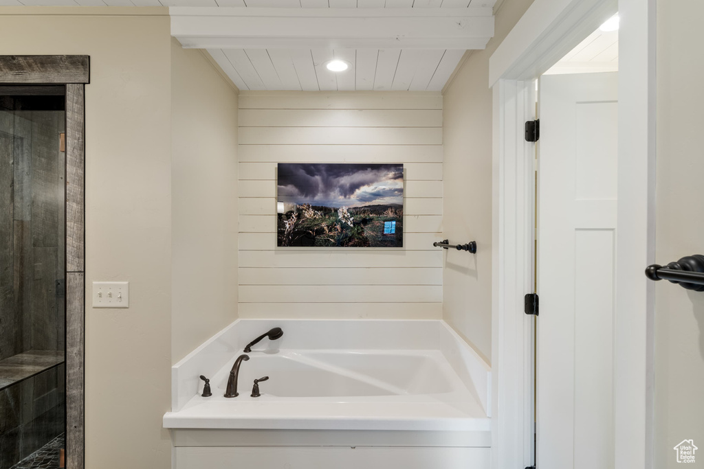 Bathroom with a garden tub, wood walls, and wooden ceiling with exposed beams