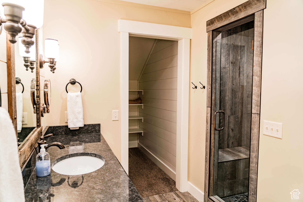 Bathroom featuring a shower stall, vanity, and a walk in closet