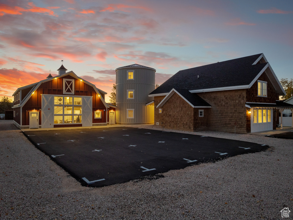 Back of property featuring a barn, uncovered parking, an outdoor structure, and a shingled roof