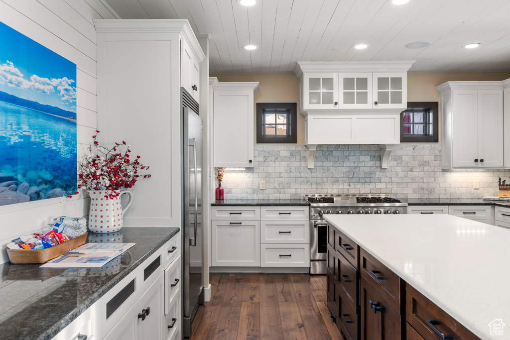 Kitchen with appliances with stainless steel finishes, recessed lighting, dark wood-type flooring, white cabinetry, and backsplash