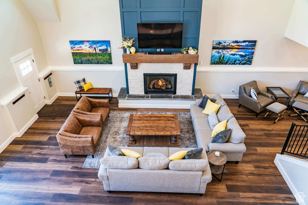 Living area with wood finished floors, a stone fireplace, and baseboards