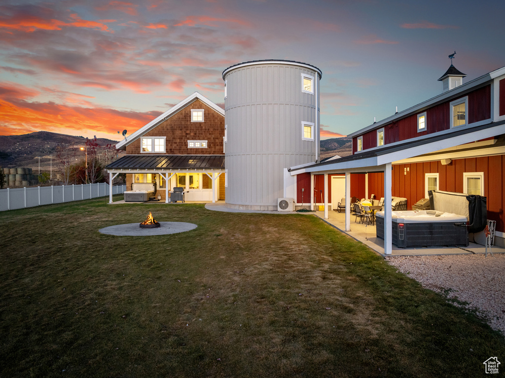 Back of property at dusk with an outdoor living space with a fire pit, a patio, metal roof, and a standing seam roof