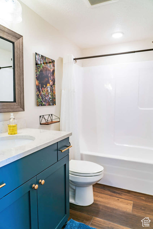 Bathroom featuring vanity, shower / bath combo with shower curtain, toilet, and wood finished floors
