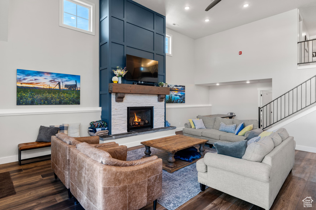 Living area with a towering ceiling, stairway, dark wood finished floors, recessed lighting, and a stone fireplace