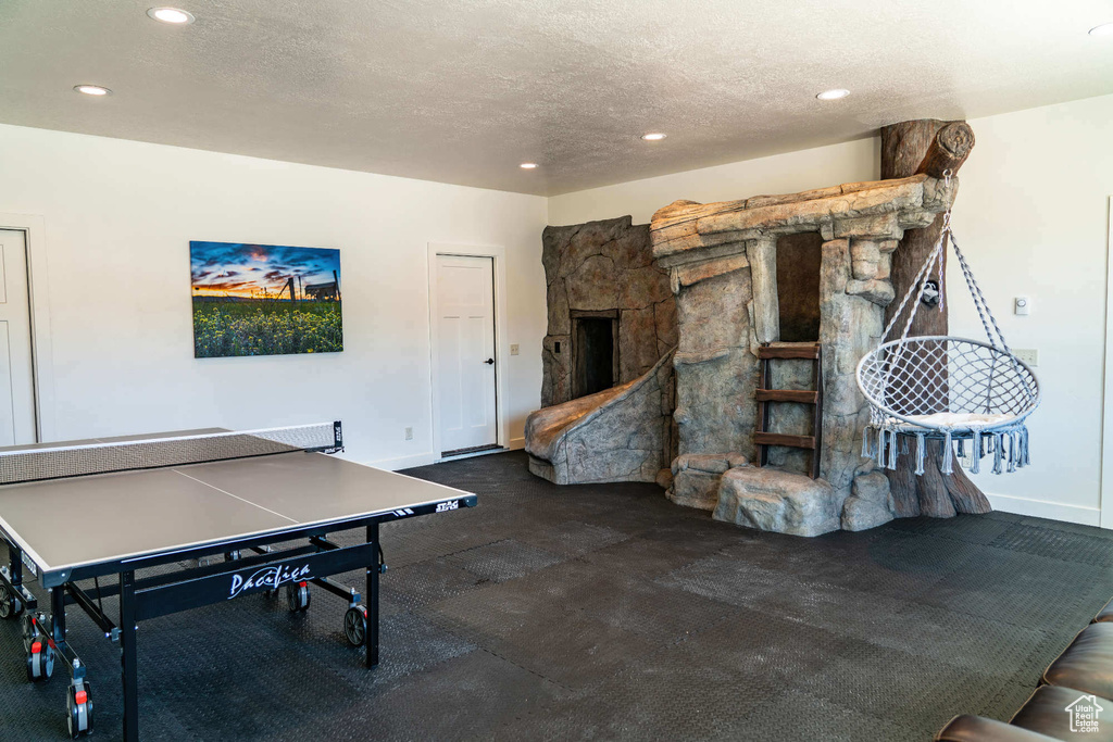 Playroom featuring recessed lighting, baseboards, a textured ceiling, and a fireplace