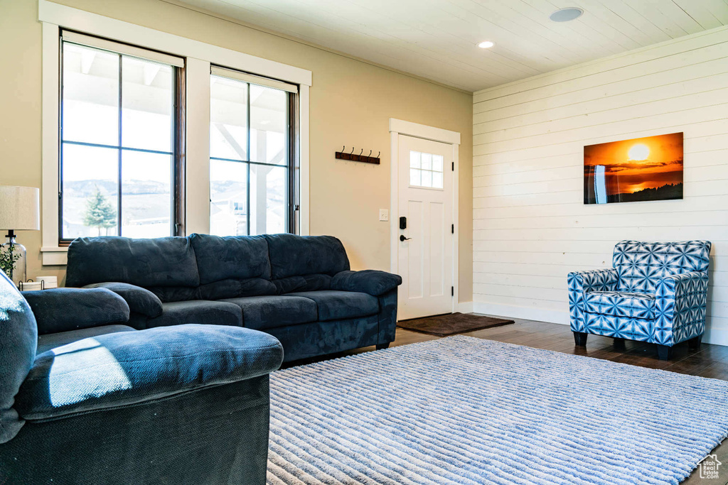 Living room with dark wood-style flooring, wooden walls, recessed lighting, and baseboards