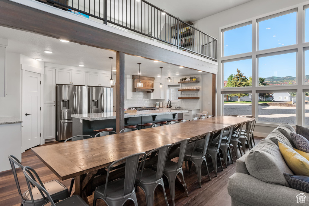 Dining room with dark wood finished floors, a towering ceiling, and recessed lighting