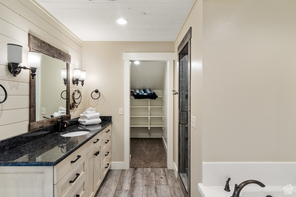 Full bathroom with wood finished floors, vanity, a walk in closet, and a shower with door