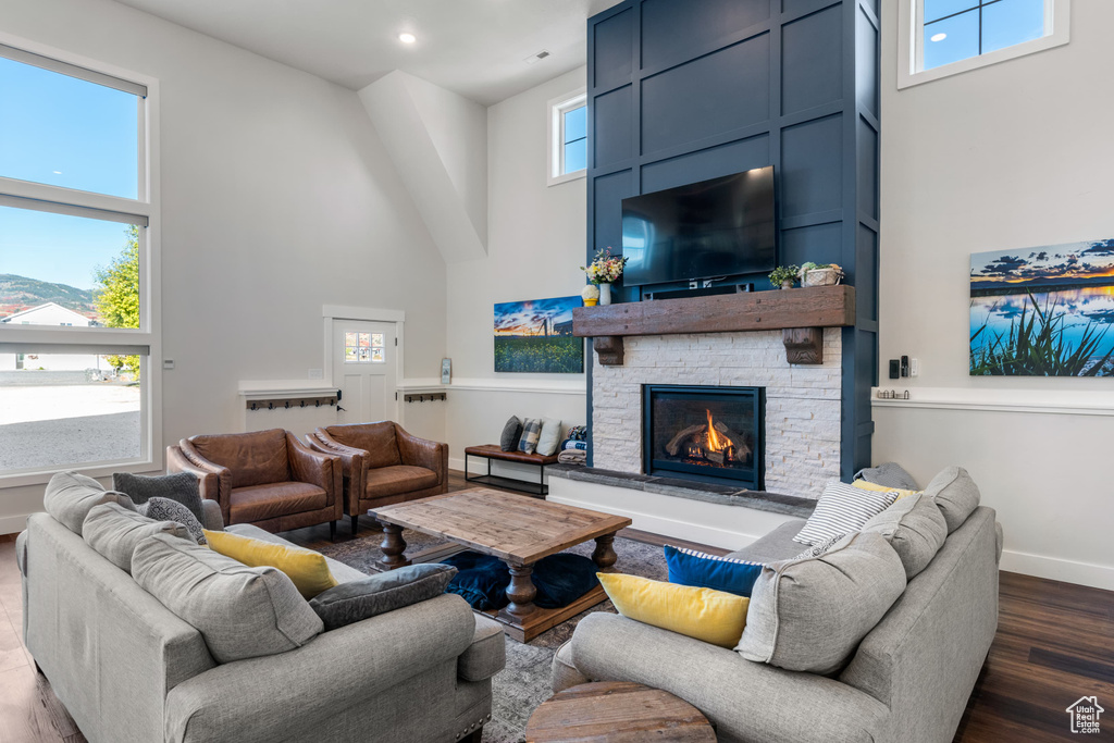 Living area featuring a towering ceiling, dark wood finished floors, a fireplace, and baseboards