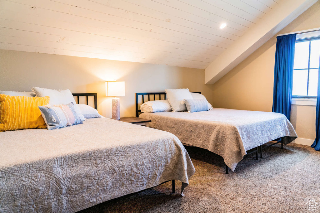 Carpeted bedroom featuring vaulted ceiling and wood ceiling