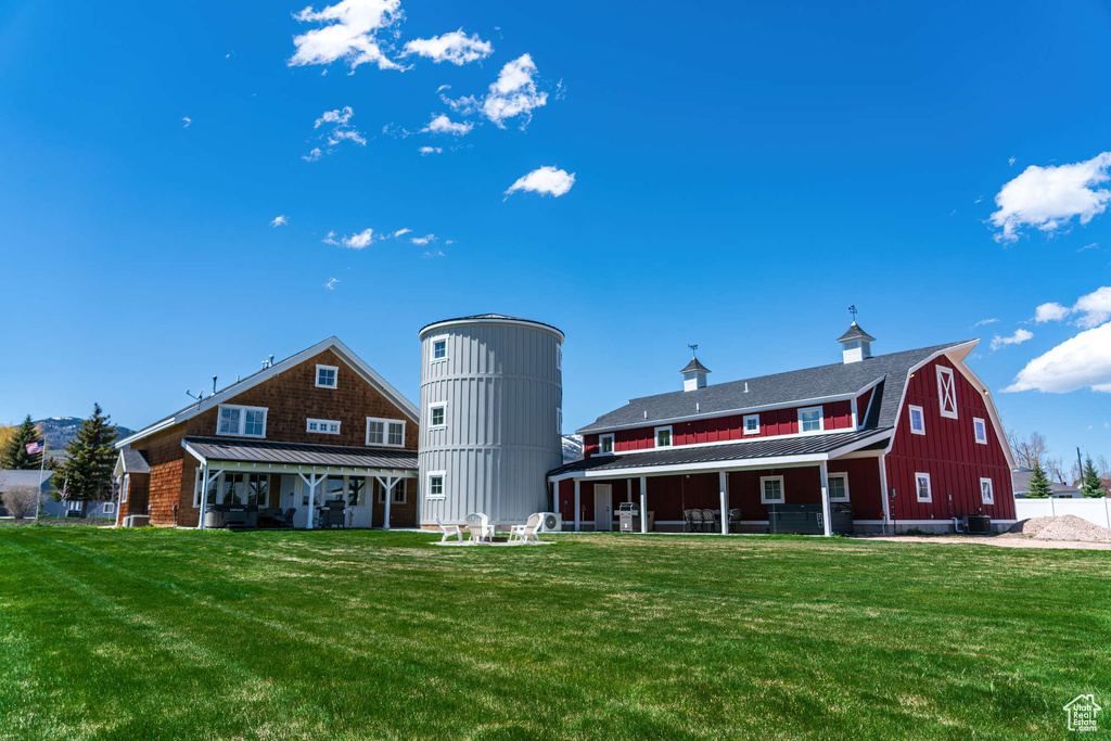 Back of property with a barn, a lawn, and metal roof
