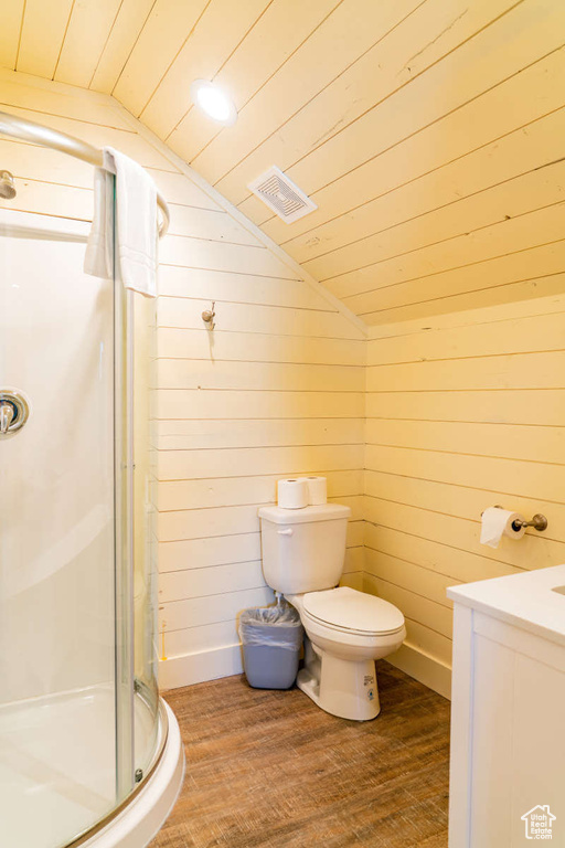 Bathroom featuring vaulted ceiling, a stall shower, wood finished floors, toilet, and vanity